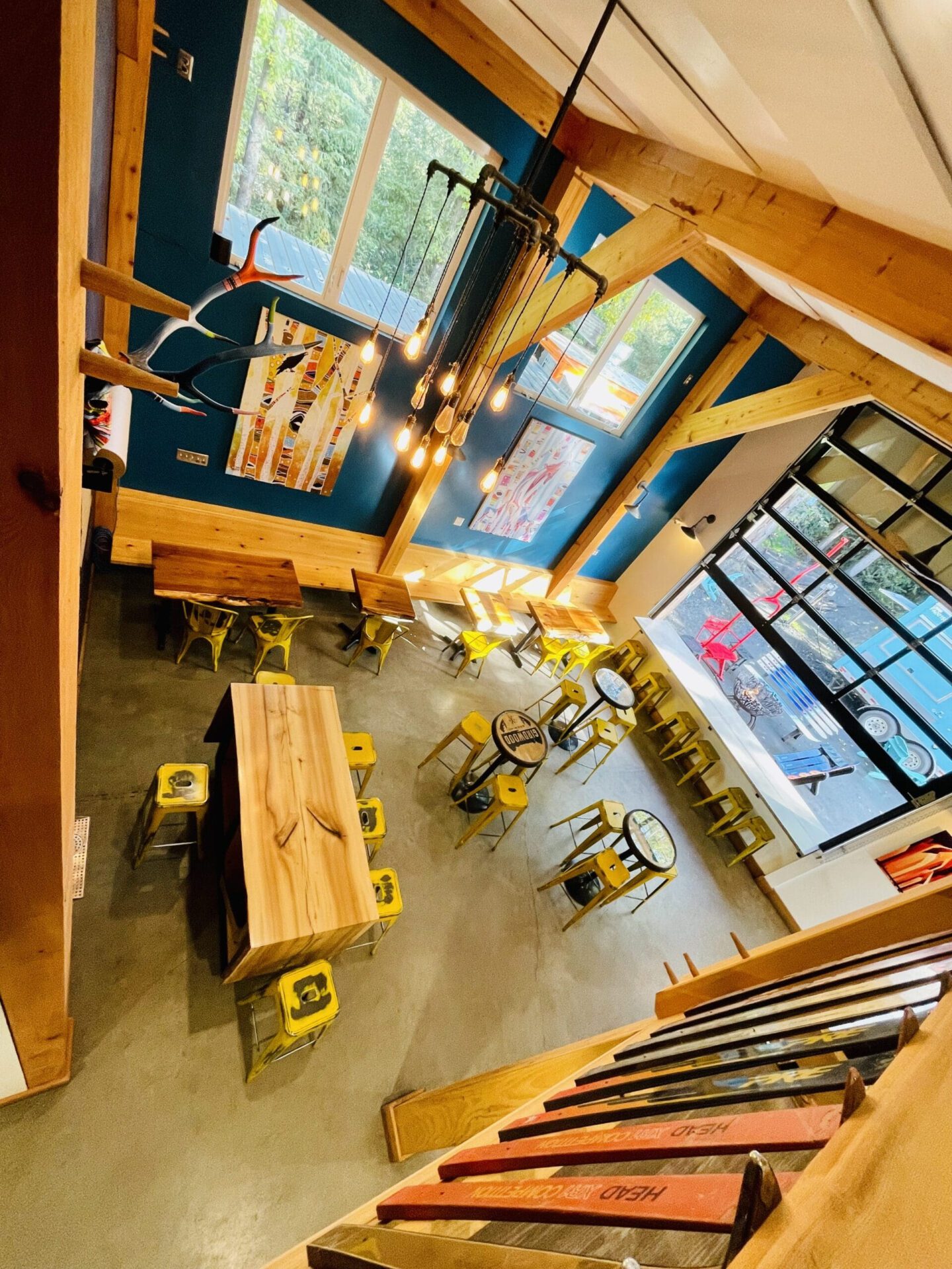 White Raven Tours Alaska guests enjoy local craft beer inside Girdwood Brewing Company’s timber-framed taproom, decorated with Alaskan art and ski relics in Girdwood, Alaska.